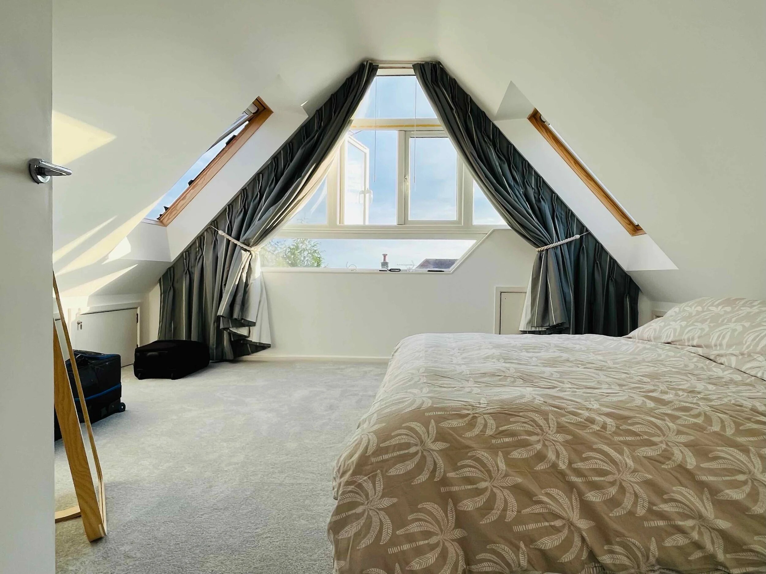 Attic bedroom with interlined curtains shaped to a steep apex window