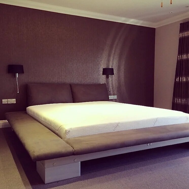 Bedroom with a wide upholstered headboard and full-length curtains